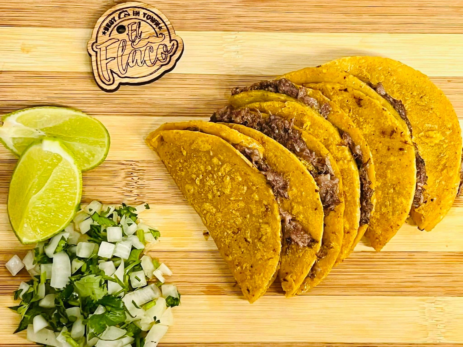 Tacos with lime, onion, and cilantro on a wooden board